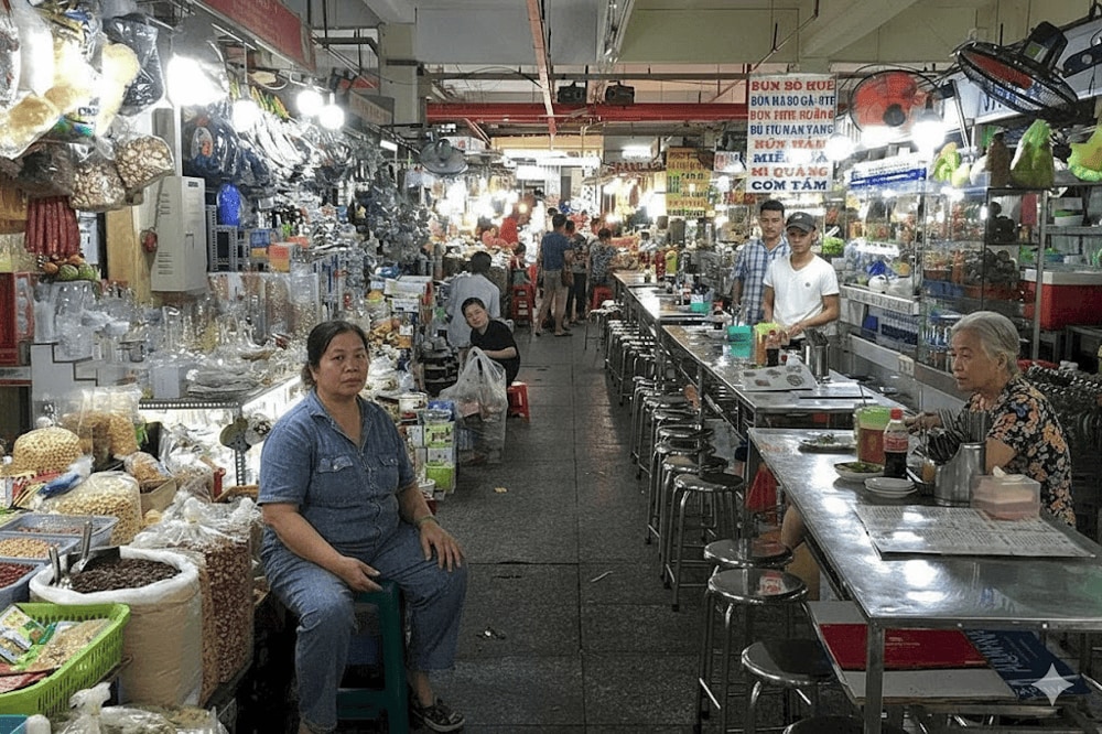 A bustling food court inside An Dong Market with its menu board in Vietnamese