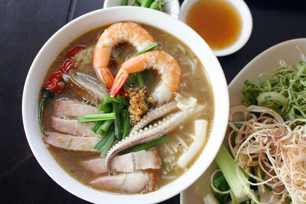 A bold, fermented shrimp paste-based broth that gives the dish a unique, deep umami flavor, served with noodles and a variety of vegetables and seafood