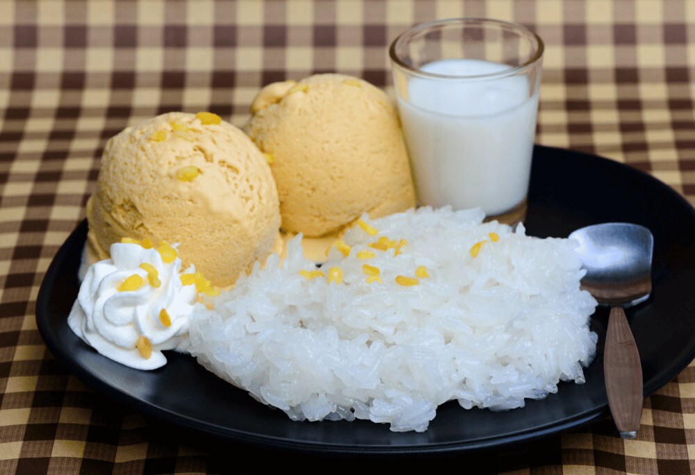 A bowl combining scoops of white coconut ice cream with sticky rice, topped with crushed coconut (Source: Canva)