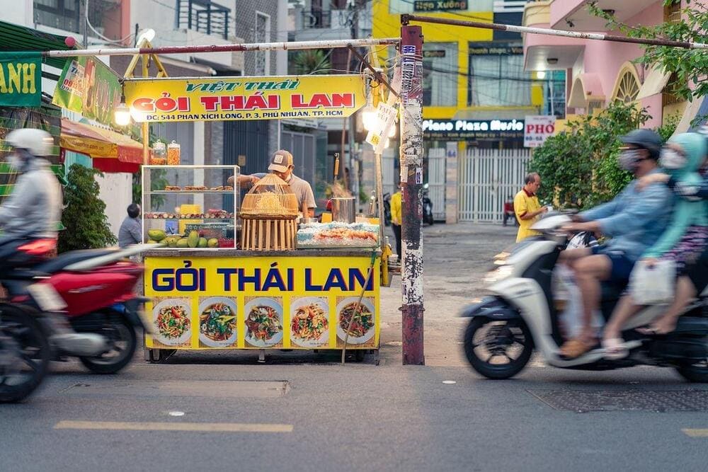 The bustling street of Phan Xich Long with food trucks on sideways