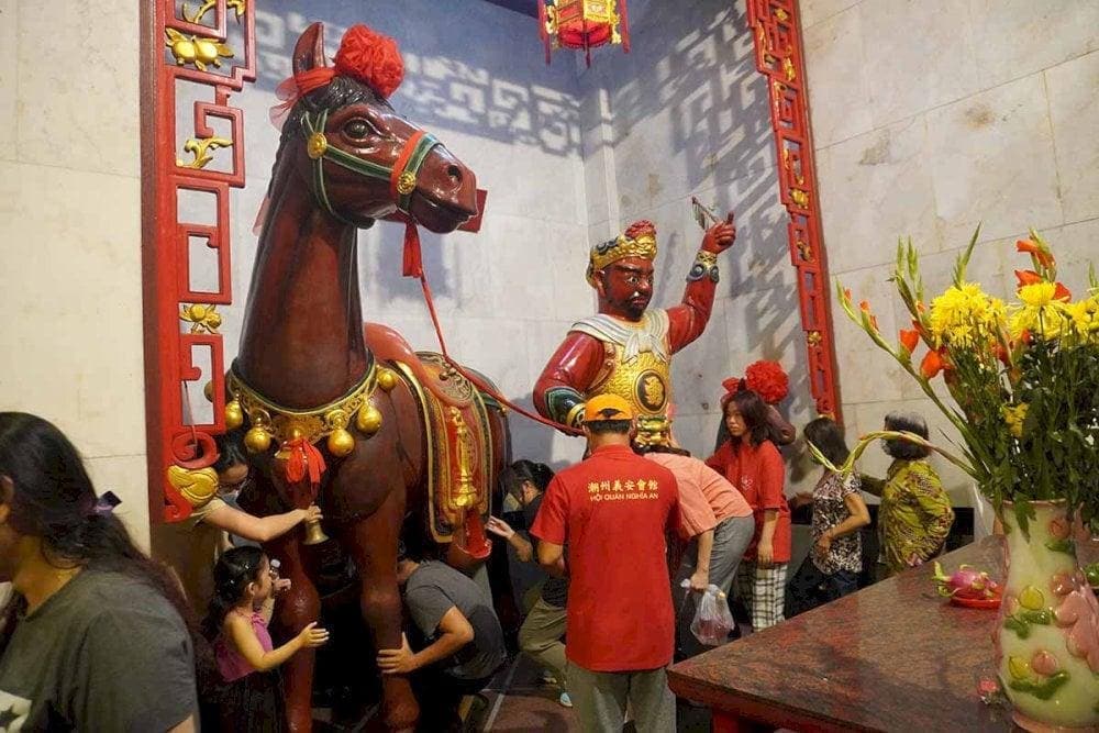 People crawl through the belly of the Red Hare horse statue to seek good fortune