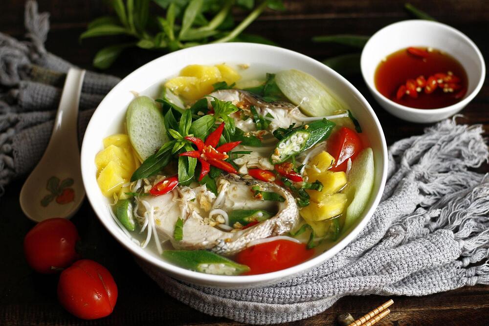 Canh chua is typically eaten with a spoon, accompanied by steamed rice