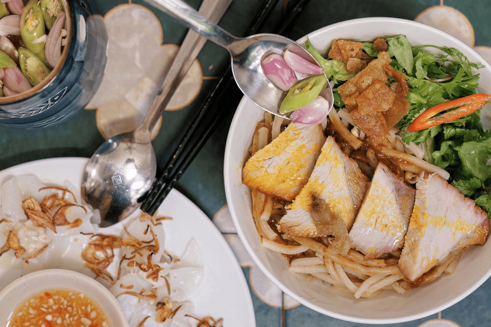 A flavorful bowl of Hoi An's iconic cao lau, where smoky pork meets crispy toppings and fresh herbs (Source: Quán Cao lầu Bá Lễ - Quán Cao lầu ngon tại Hội An)