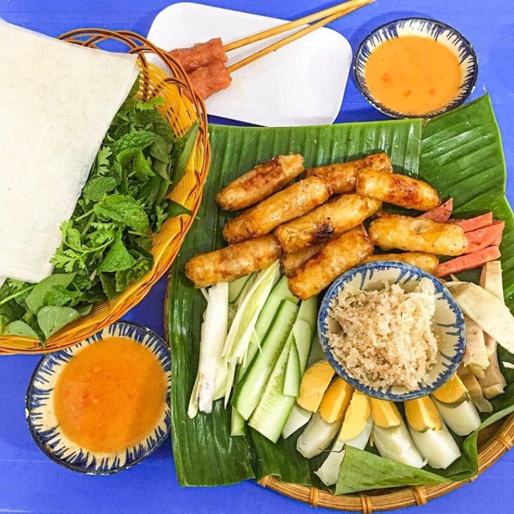 Chả giò cá trích ăn kèm dưa leo, rau sống và chấm mắm đậu phộng béo ngậy