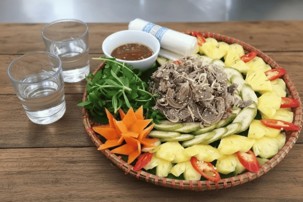 Món nem dê núi Ninh Bình tuyệt nhất khi ăn kèm với lá sung, lá ổi, khế, lá mơ, chuối xanh, rau thơm và chấm kèm tương gừng