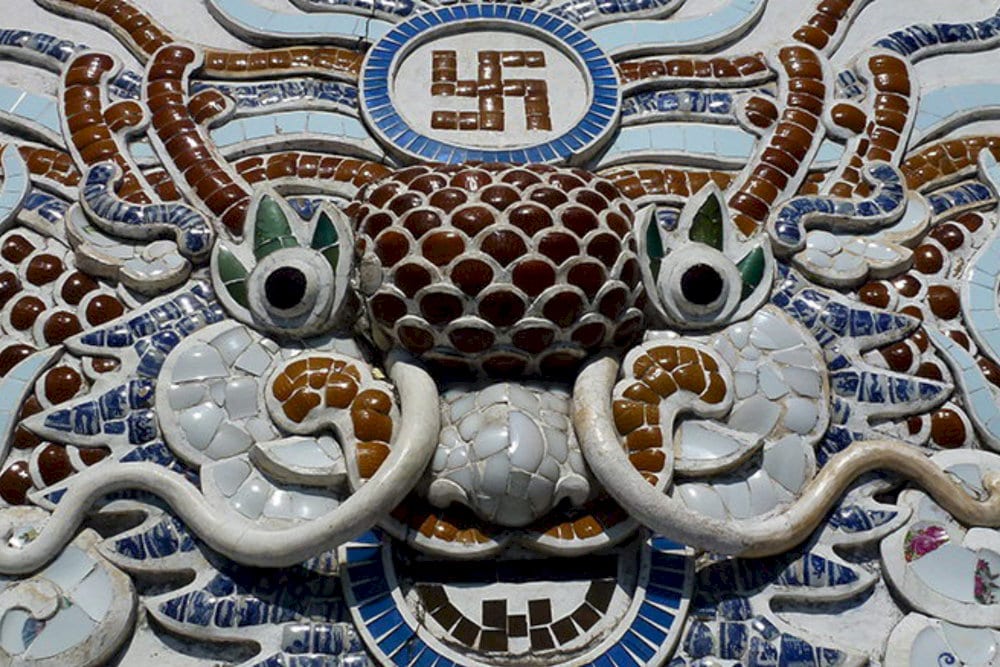 The ceramic mosaic mural of a dragon and the swastika symbol stands out with deep Buddhist symbolism