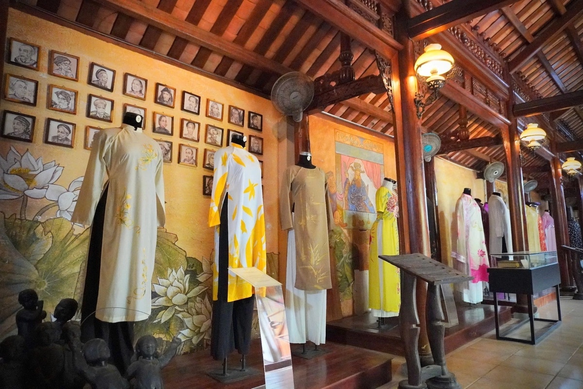 The warm, dim lighting casts a nostalgic glow, enhancing the elegance of the traditional ao dai on display