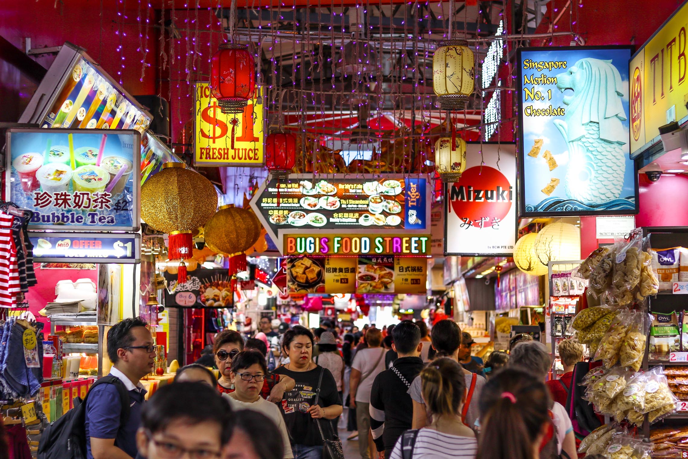 A lively Bugis food market in Singapore, with busy stalls and visitors exploring local street food