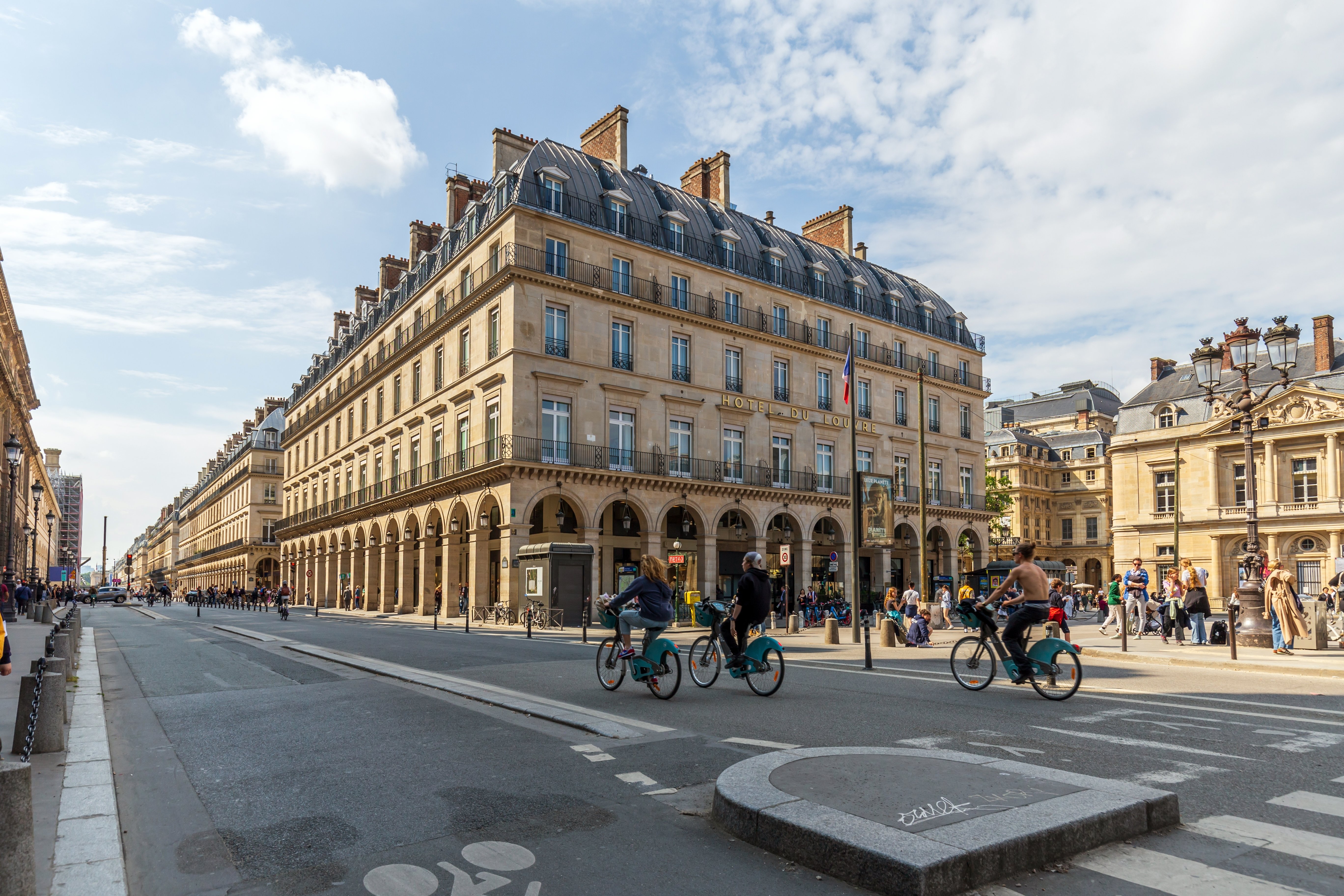 Travelers cycling past historic Parisian architecture