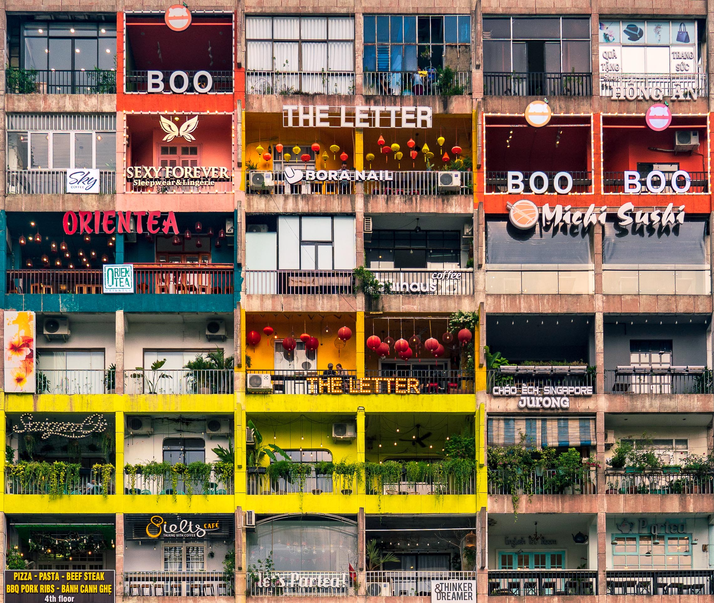 Shop and restaurant signs inside an old apartment building on Nguyen Hue Walking Street