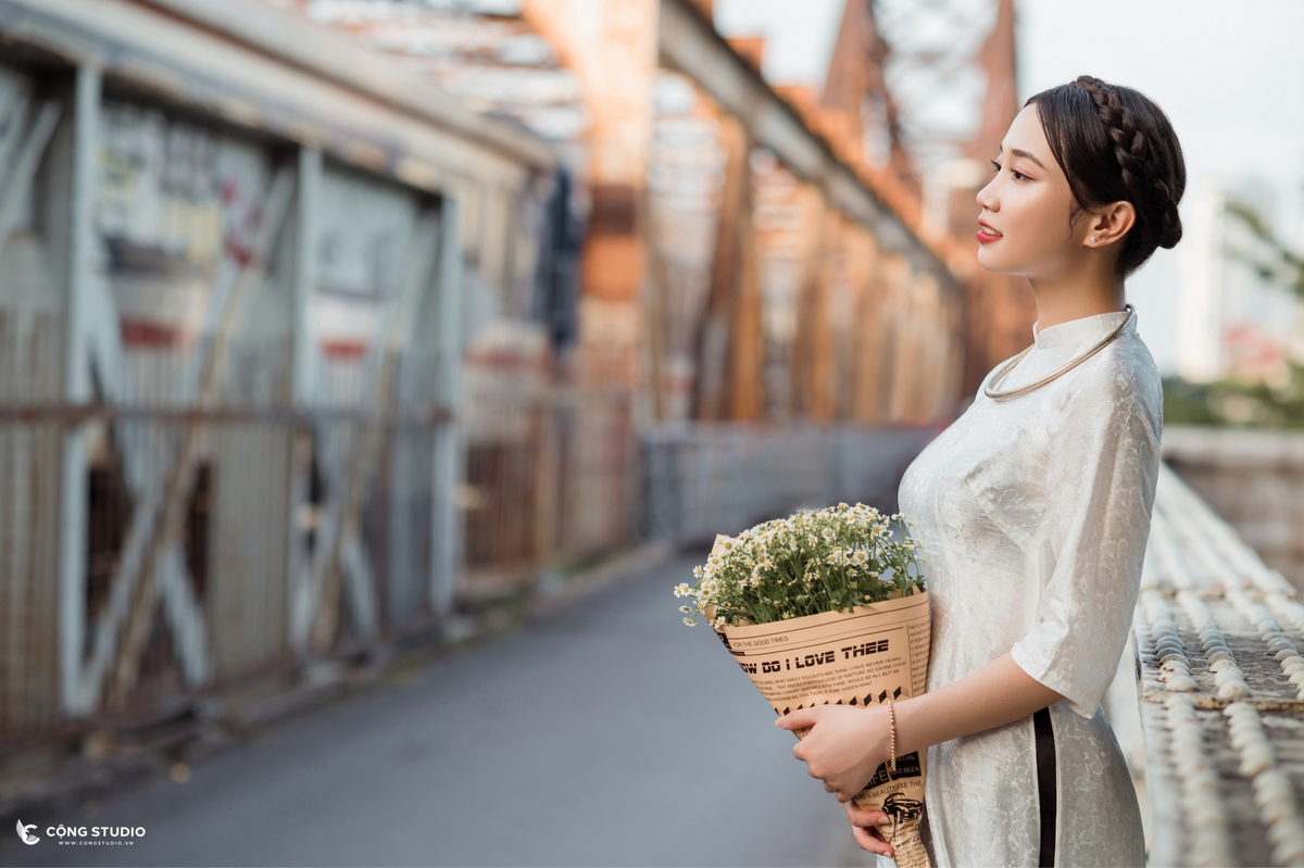 Mẫu mặc áo dài ôm hoa chụp tại lan can cầu Long Biên