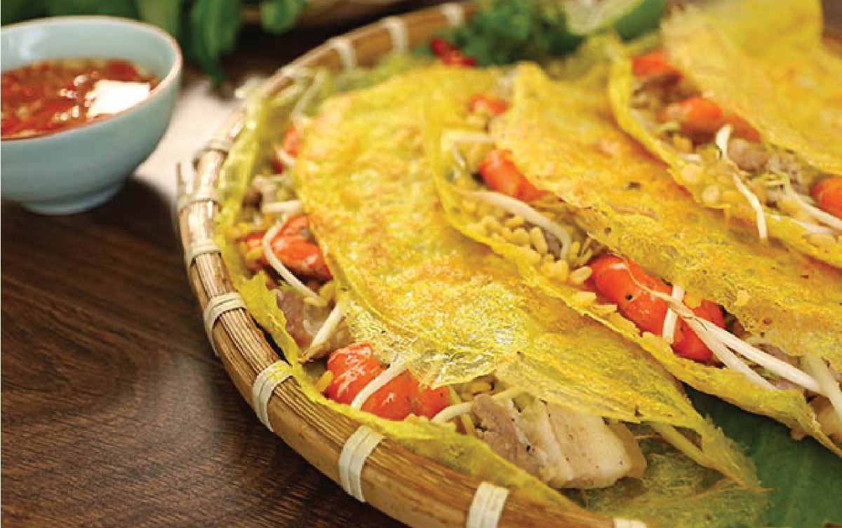 Bánh xèo với lớp vỏ vàng giòn, nhân đầy ụ ăn kèm rau sống và nước mắm chua ngọ